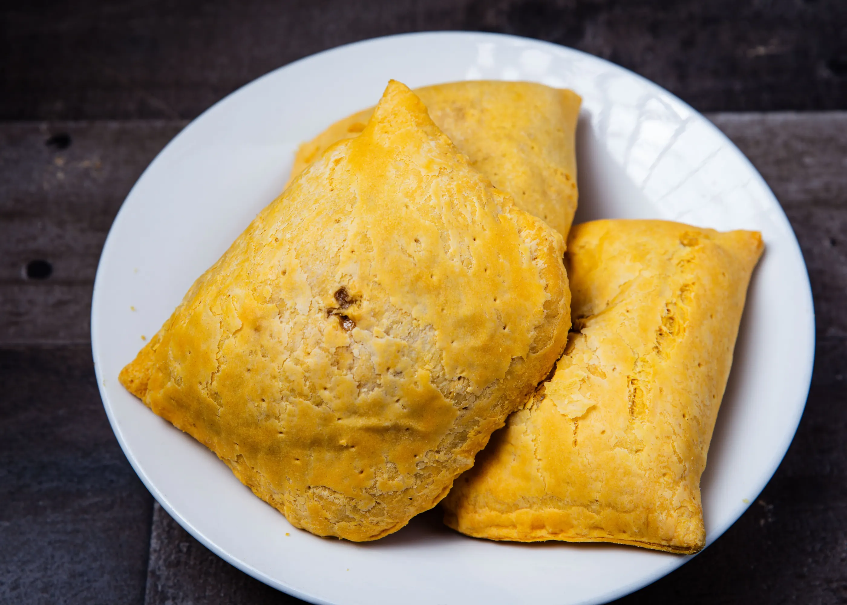 Jamaican beef patties with golden pastry on a white plate